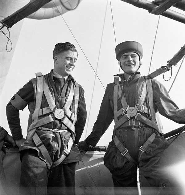 Photographie en noir et blanc – Photographie en noir et blanc – Deux hommes en uniforme militaire et portant leur parachute, en train de rire sur une piste.
